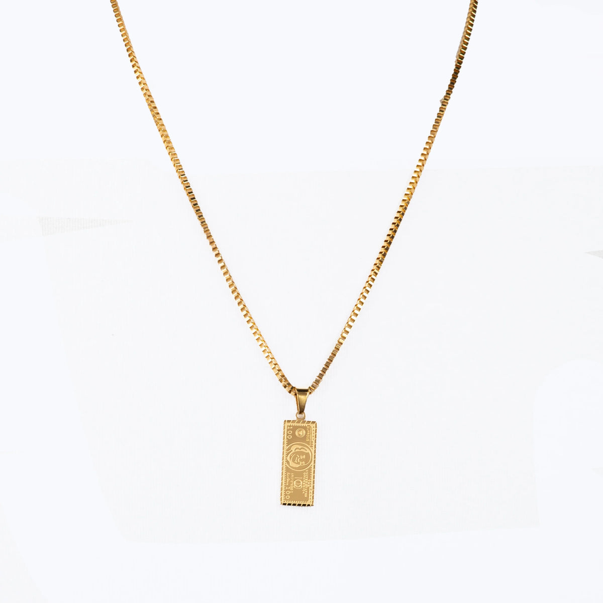 Gold-colored necklace with a rectangular pendant featuring a dollar bill design.