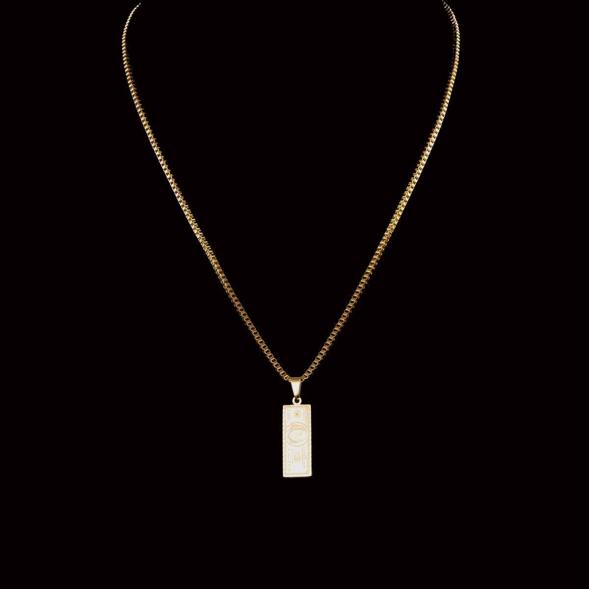 Gold necklace with a rectangular pendant featuring embossed designs.