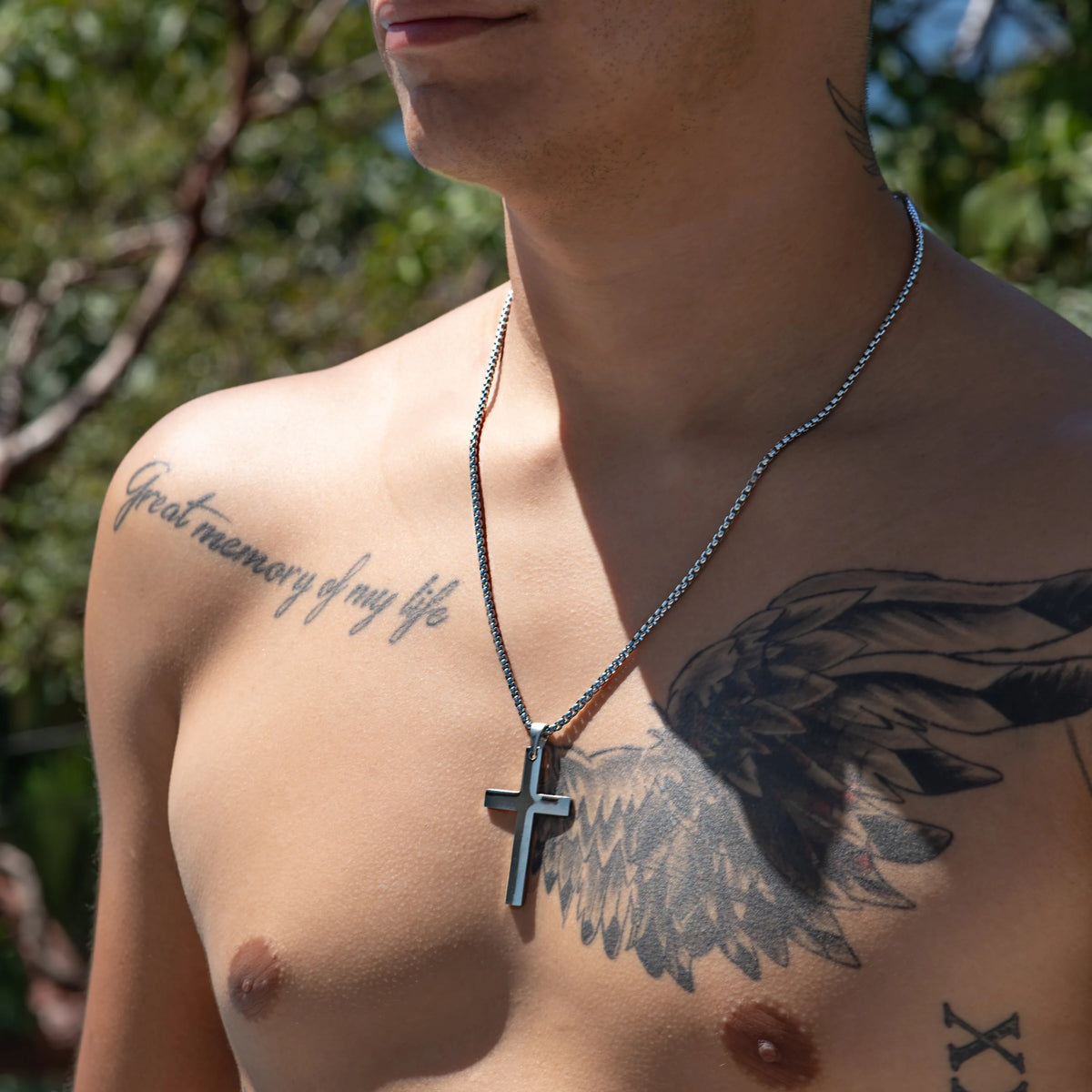 Shirtless torso with tattoos and a cross necklace.