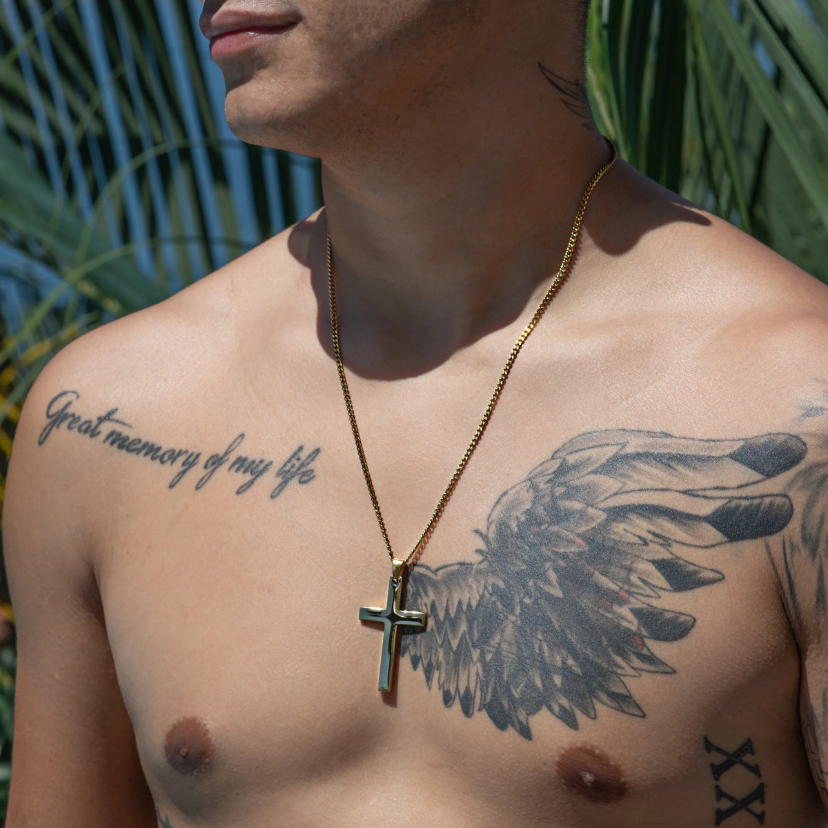 Shirtless torso with tattoos and a gold cross necklace.