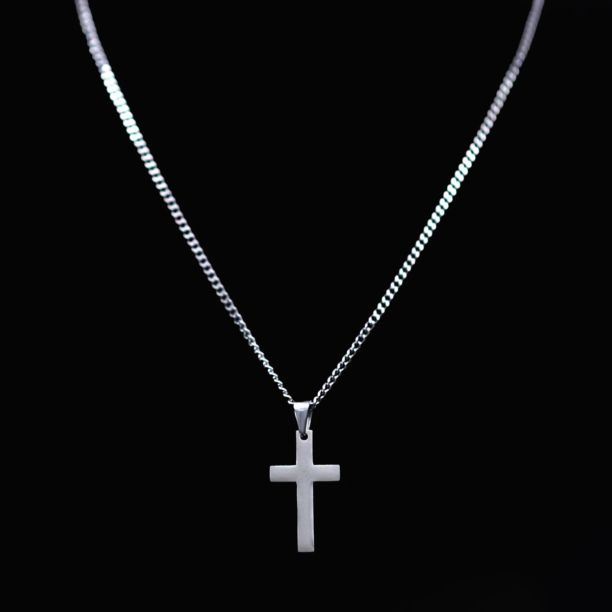 Silver cross pendant on a thin chain necklace.