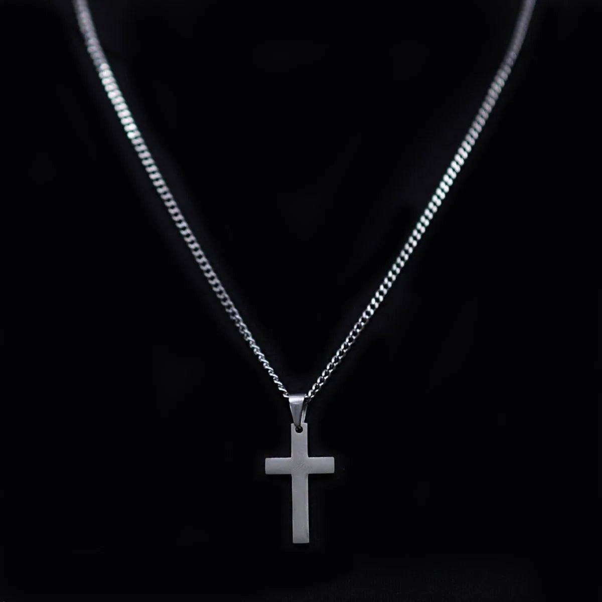 Silver cross pendant on a thin chain necklace.