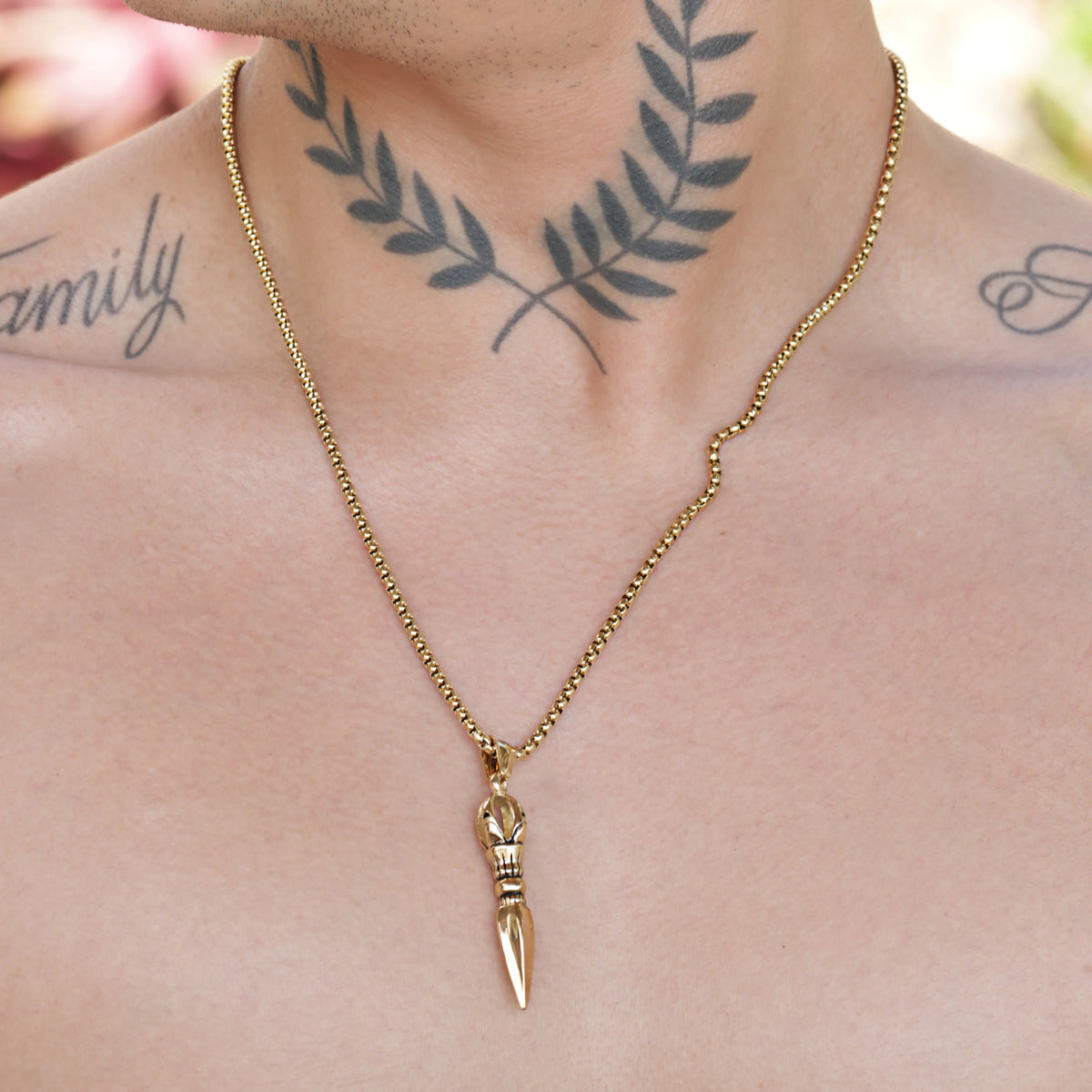 Gold pendant necklace featuring a bullet-shaped charm on a chain.