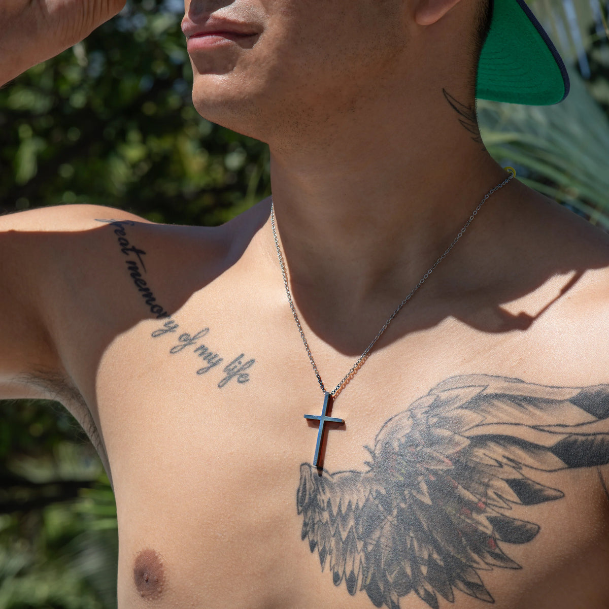 Shirtless person with tattoos and a cross necklace.