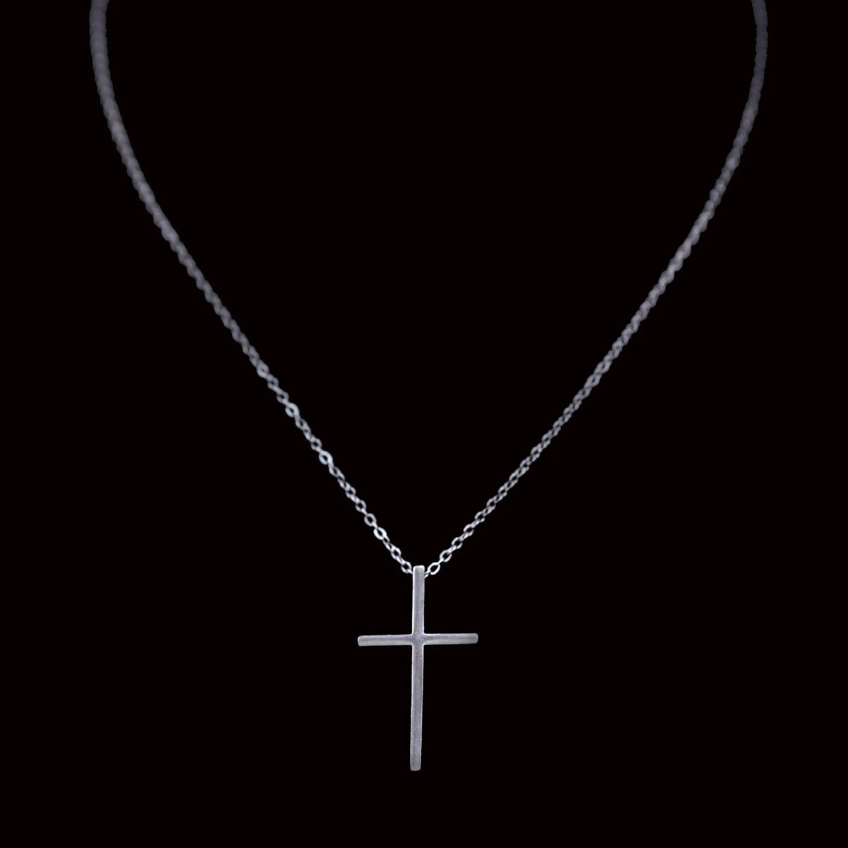 Silver cross pendant necklace on a delicate chain.