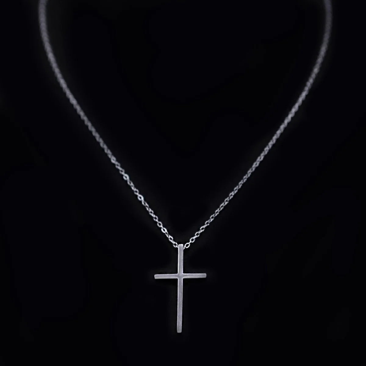 Silver cross pendant necklace on a delicate chain.