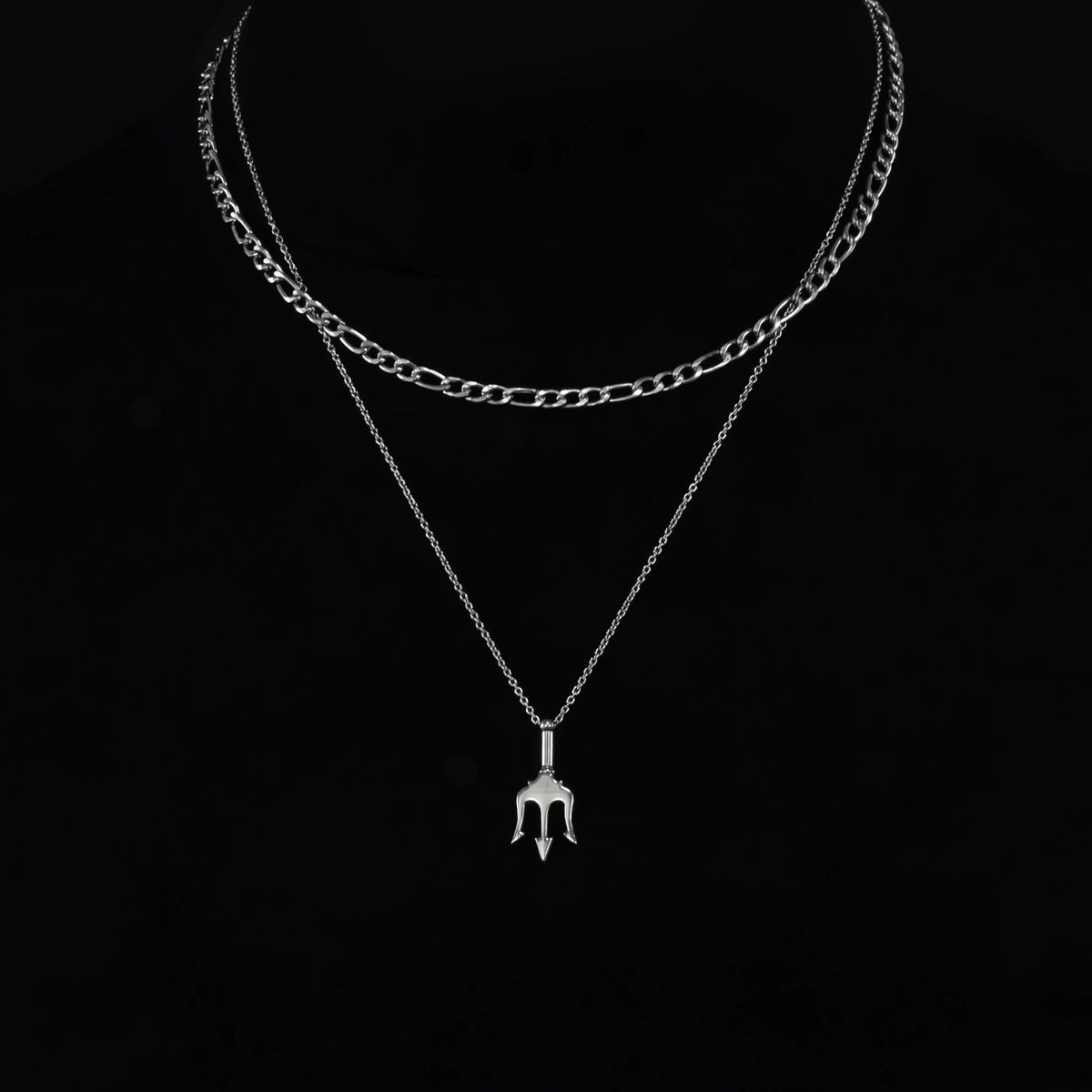 Layered silver necklace with a trident-shaped pendant.