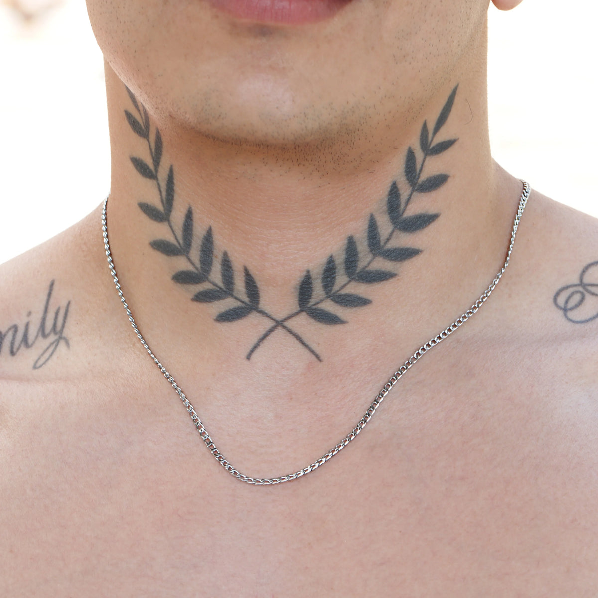 Tattoo of crossed laurel branches on a person’s neck.