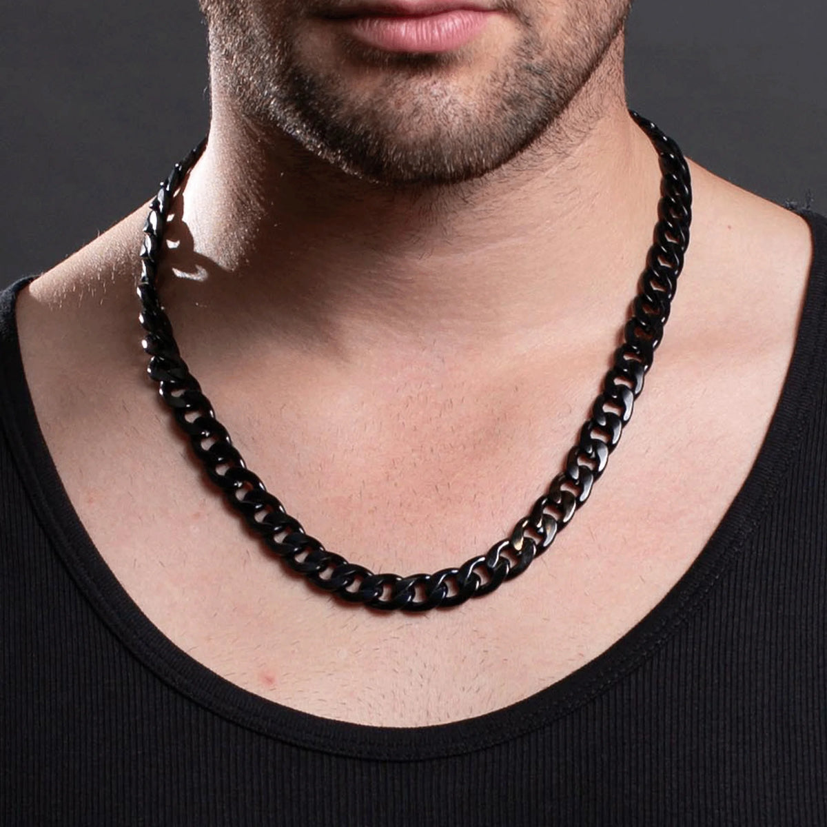 Black metal chain necklace worn around a neck.