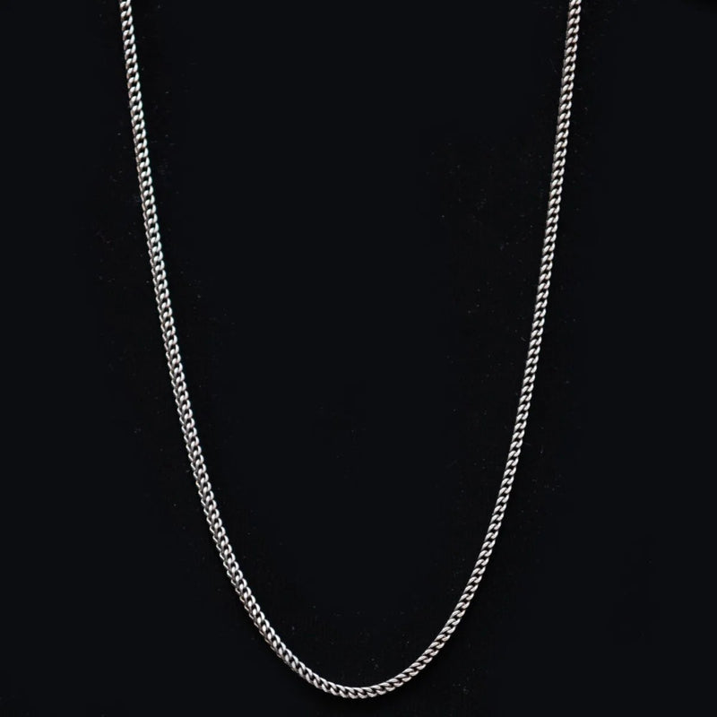 Silver chain necklace against a black background.