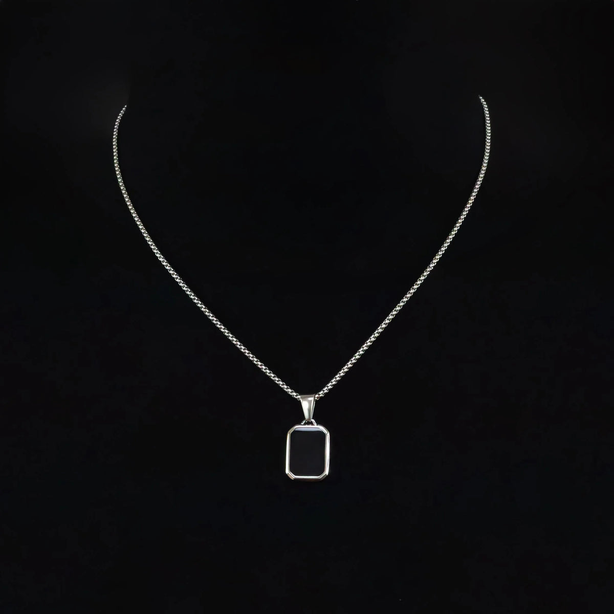 Silver necklace with a rectangular black pendant.