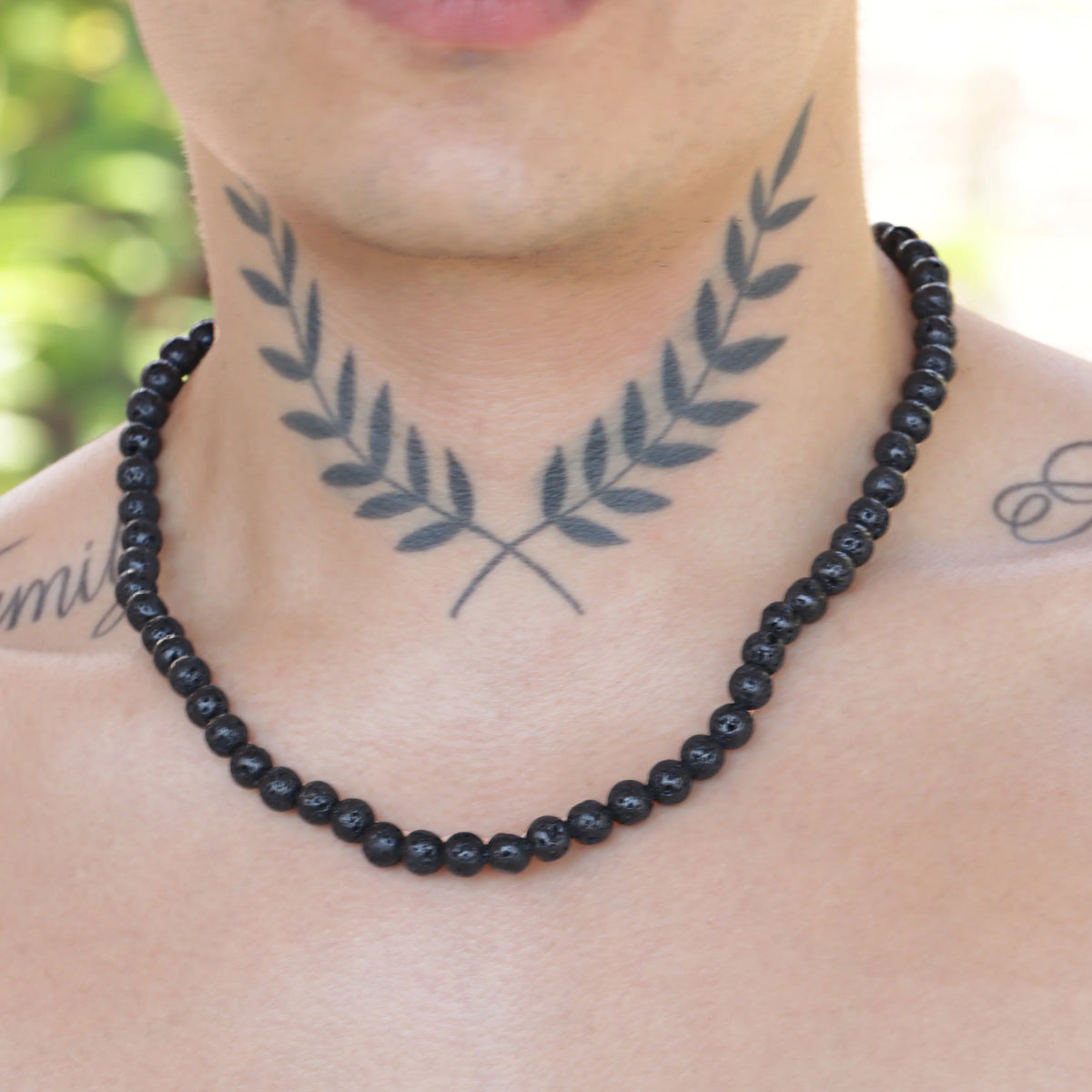 Black beaded necklace worn with a laurel wreath neck tattoo.