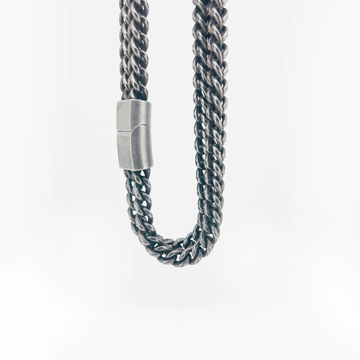 Silver chain necklace with a cylindrical clasp.