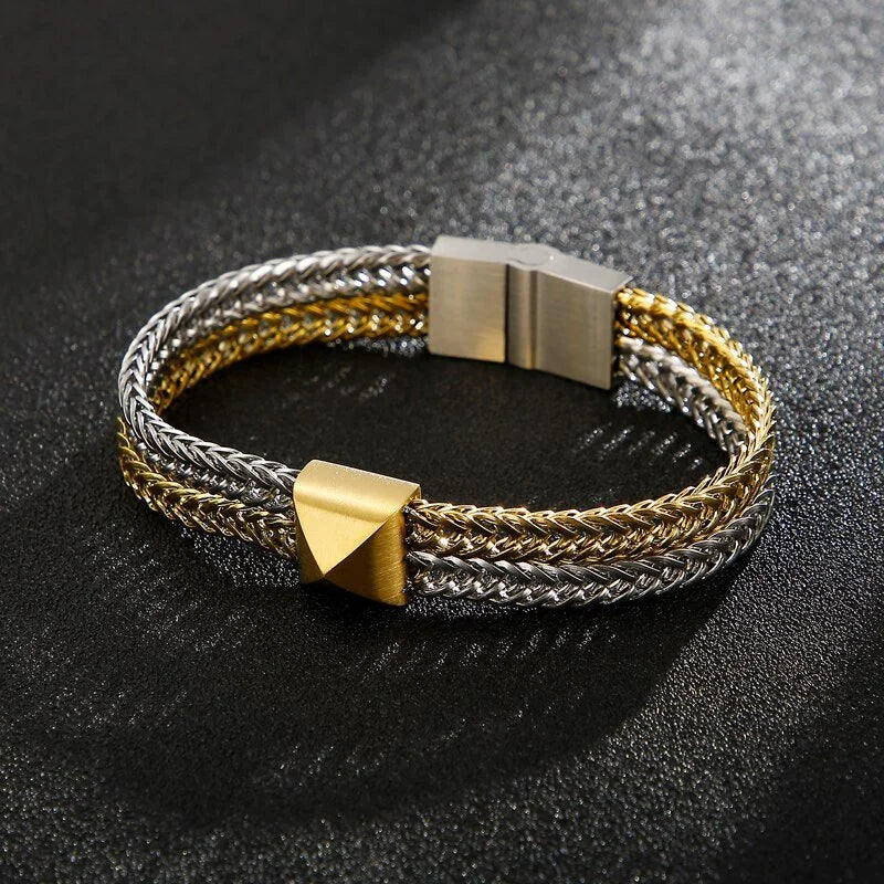 Two-tone braided metal bracelet with a gold geometric accent piece.