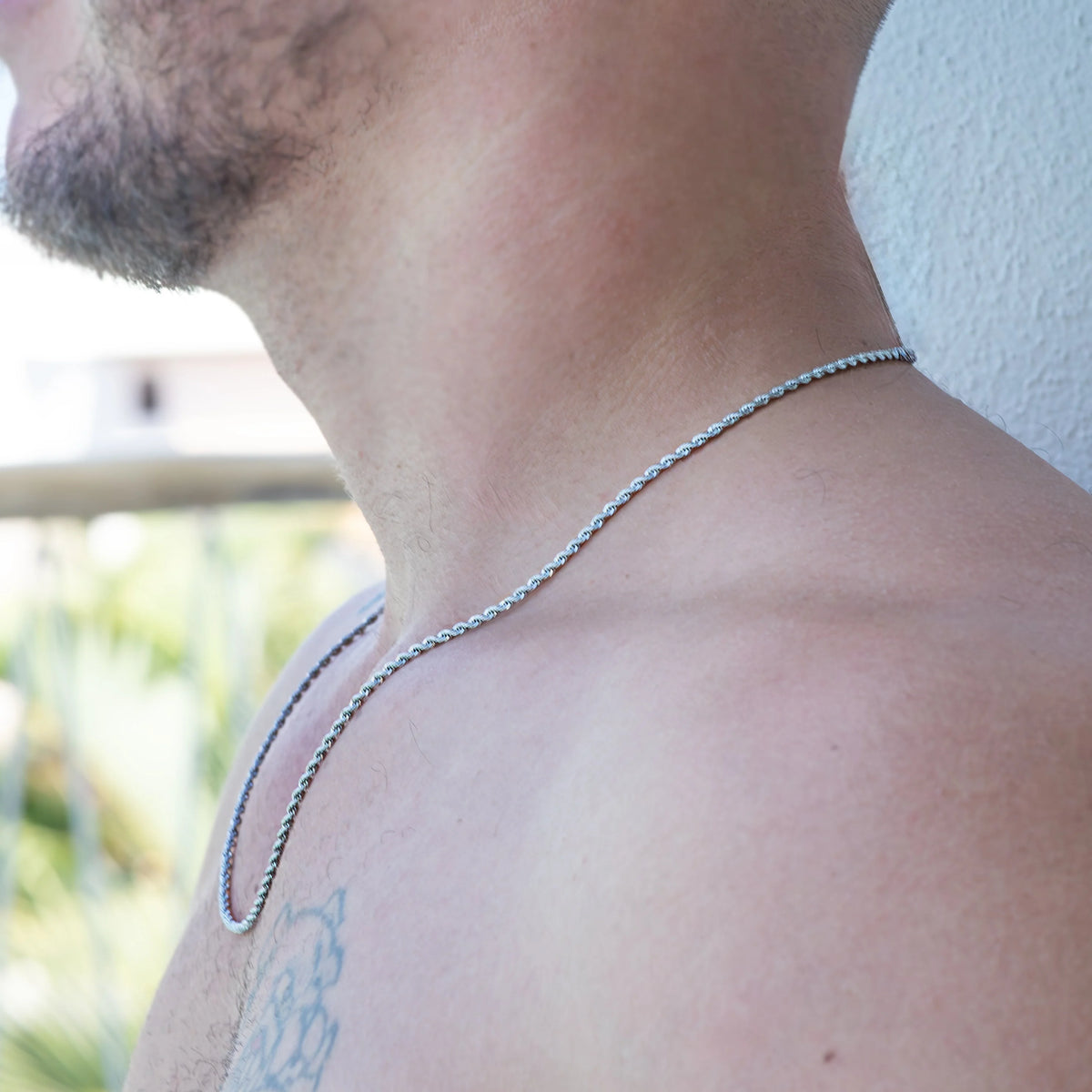 Silver chain necklace worn around a person’s neck.