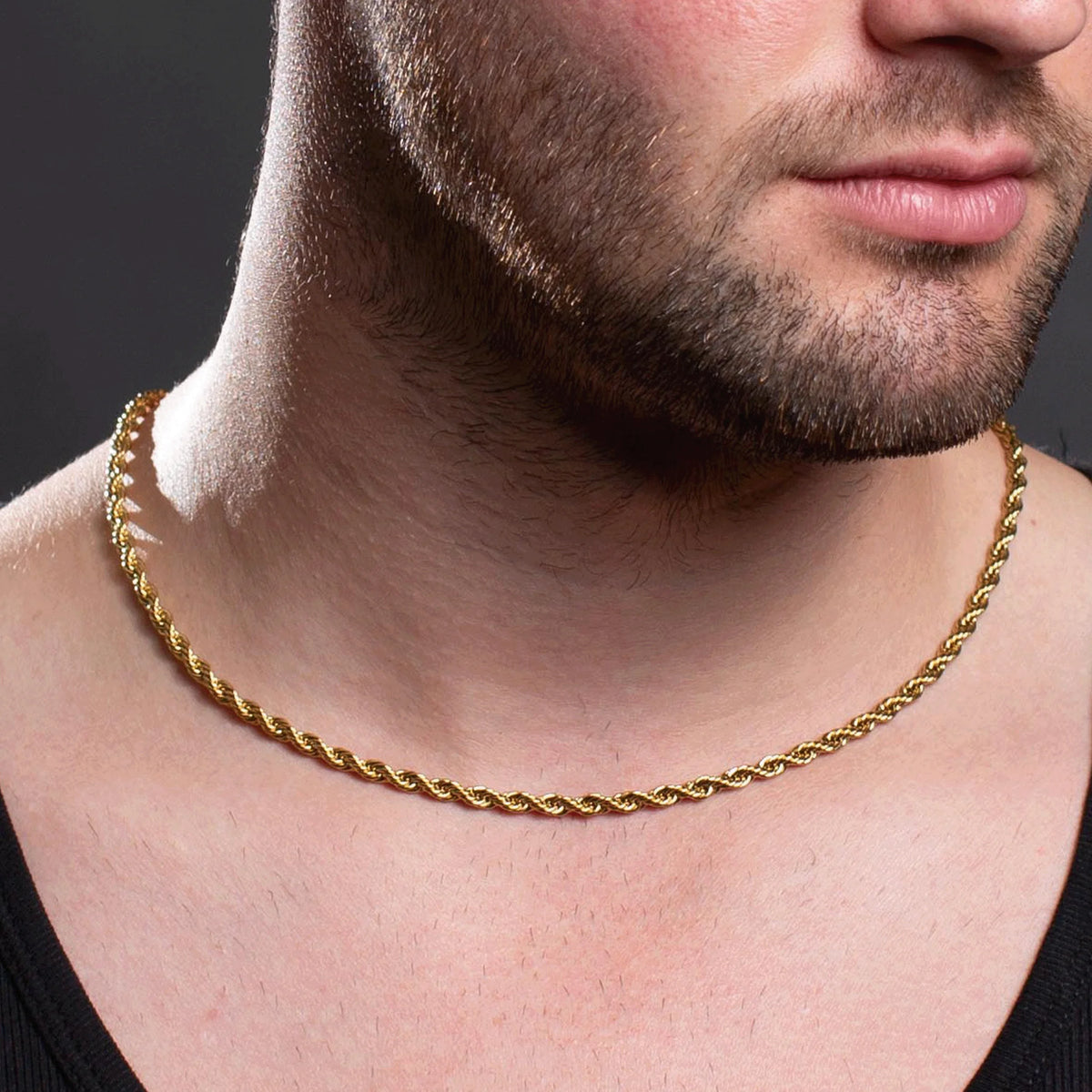 Gold rope chain necklace worn around a person’s neck.