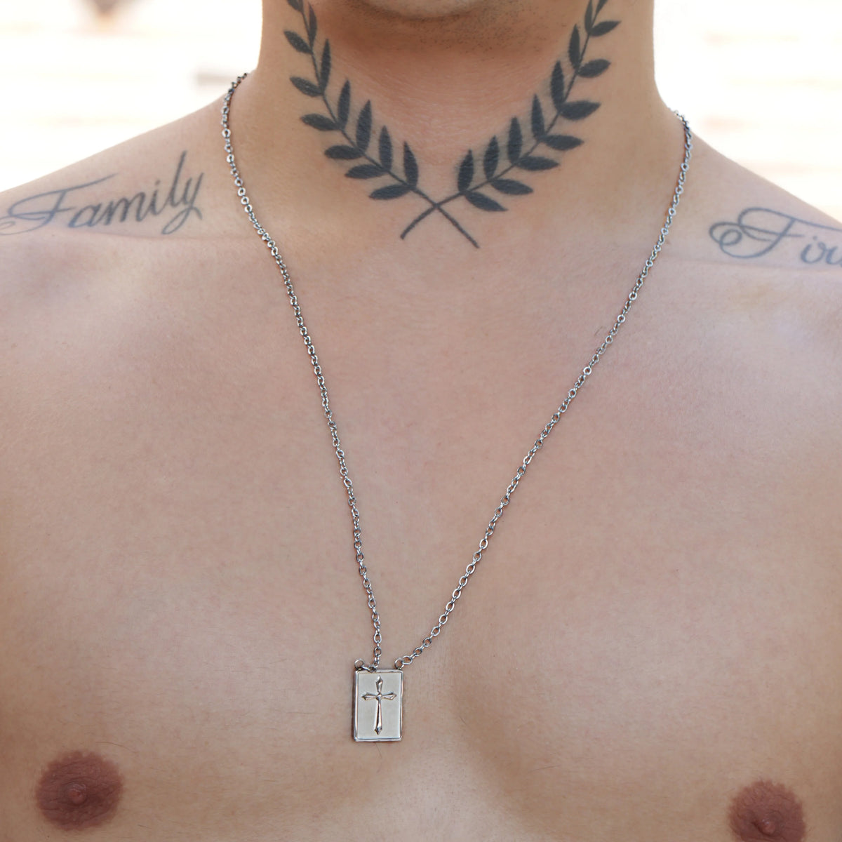 Silver necklace with a rectangular pendant featuring a cross design.