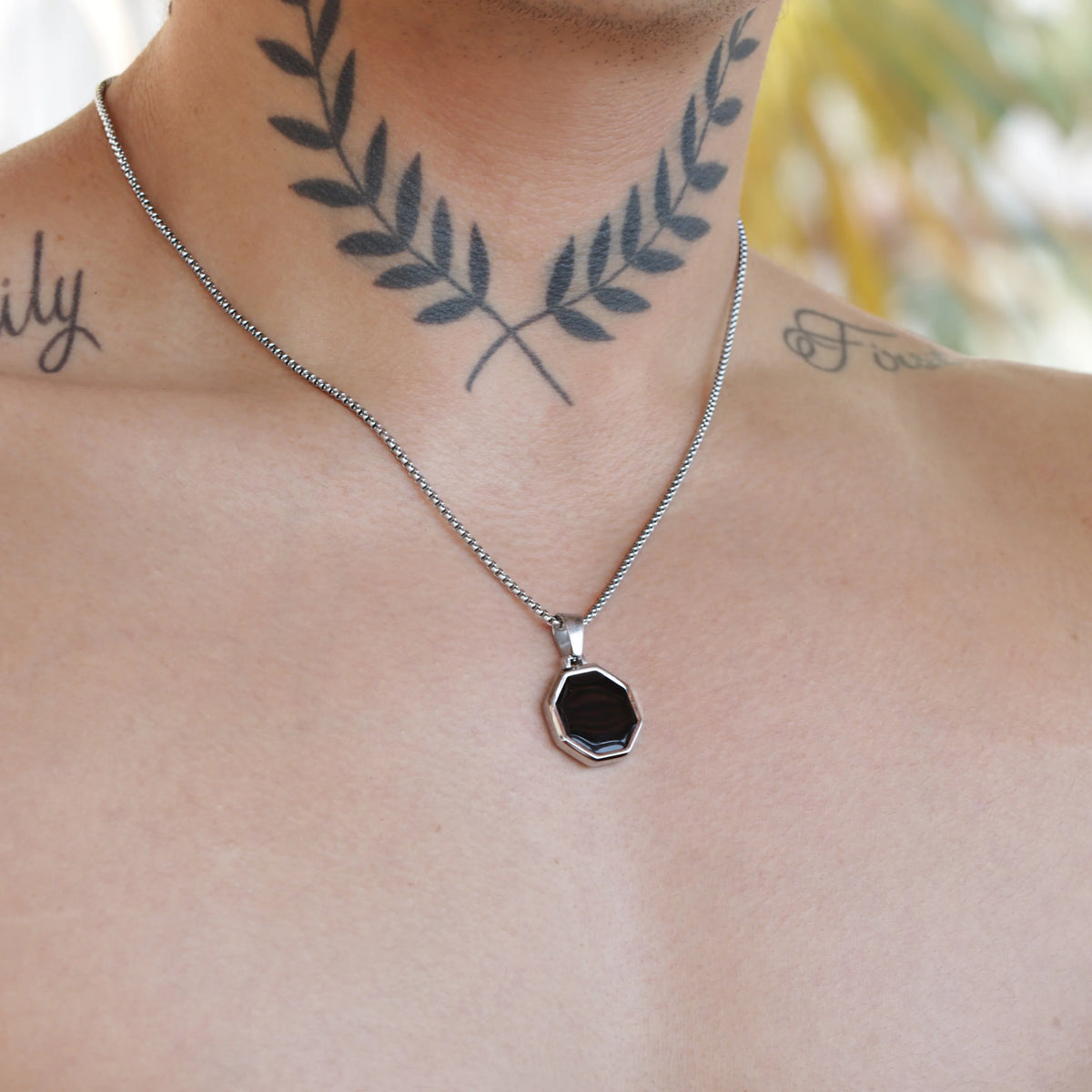 Silver necklace with a black octagonal pendant.