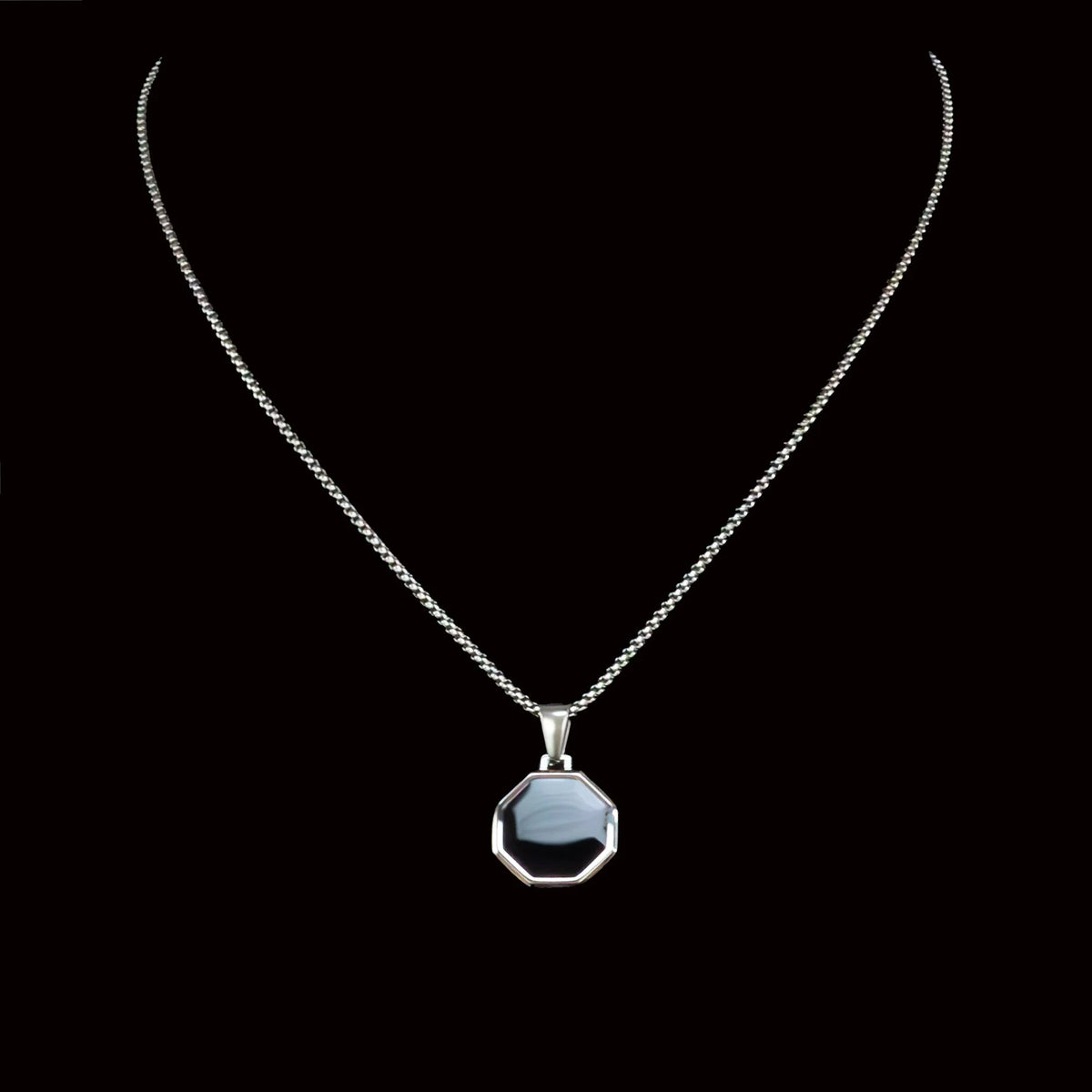 Silver necklace with an octagonal black pendant.