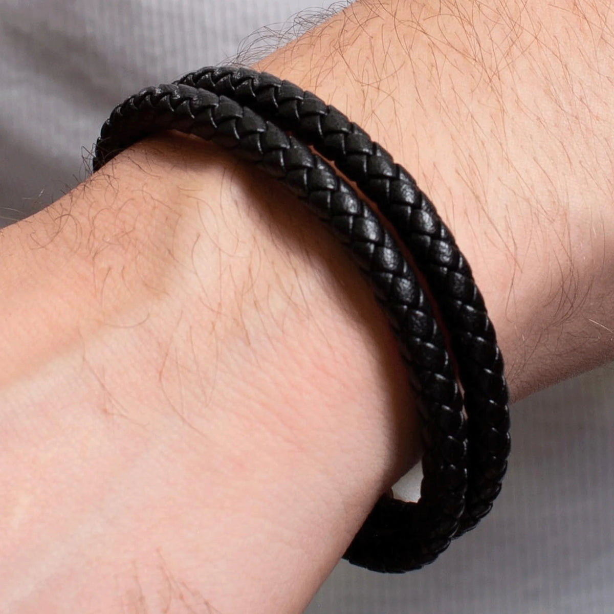 Black braided leather bracelet worn on a wrist.