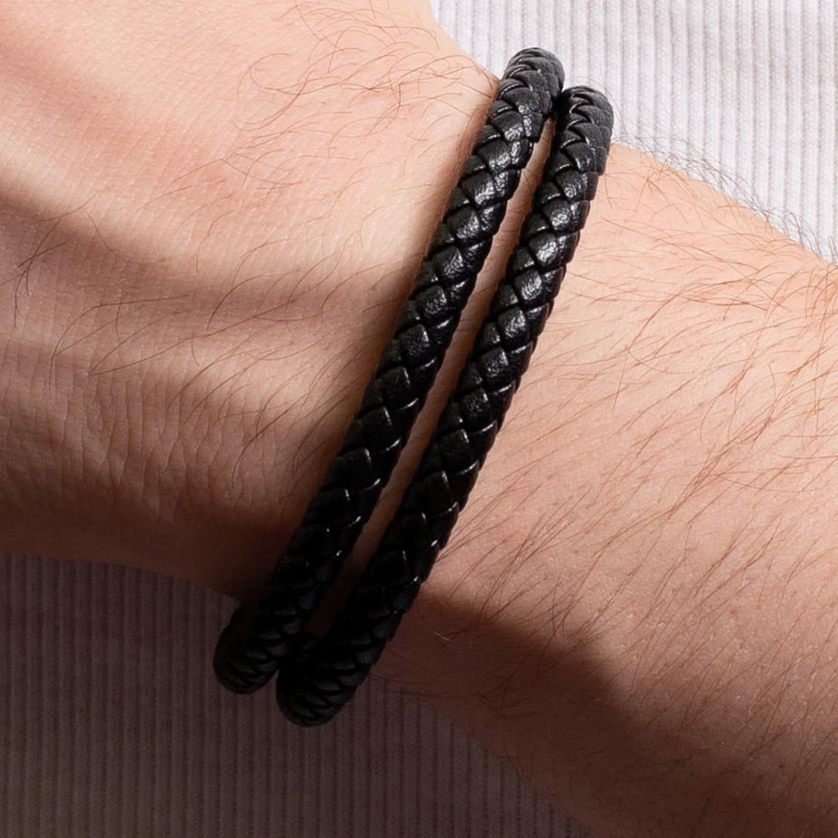 Black braided leather bracelet worn on a wrist.