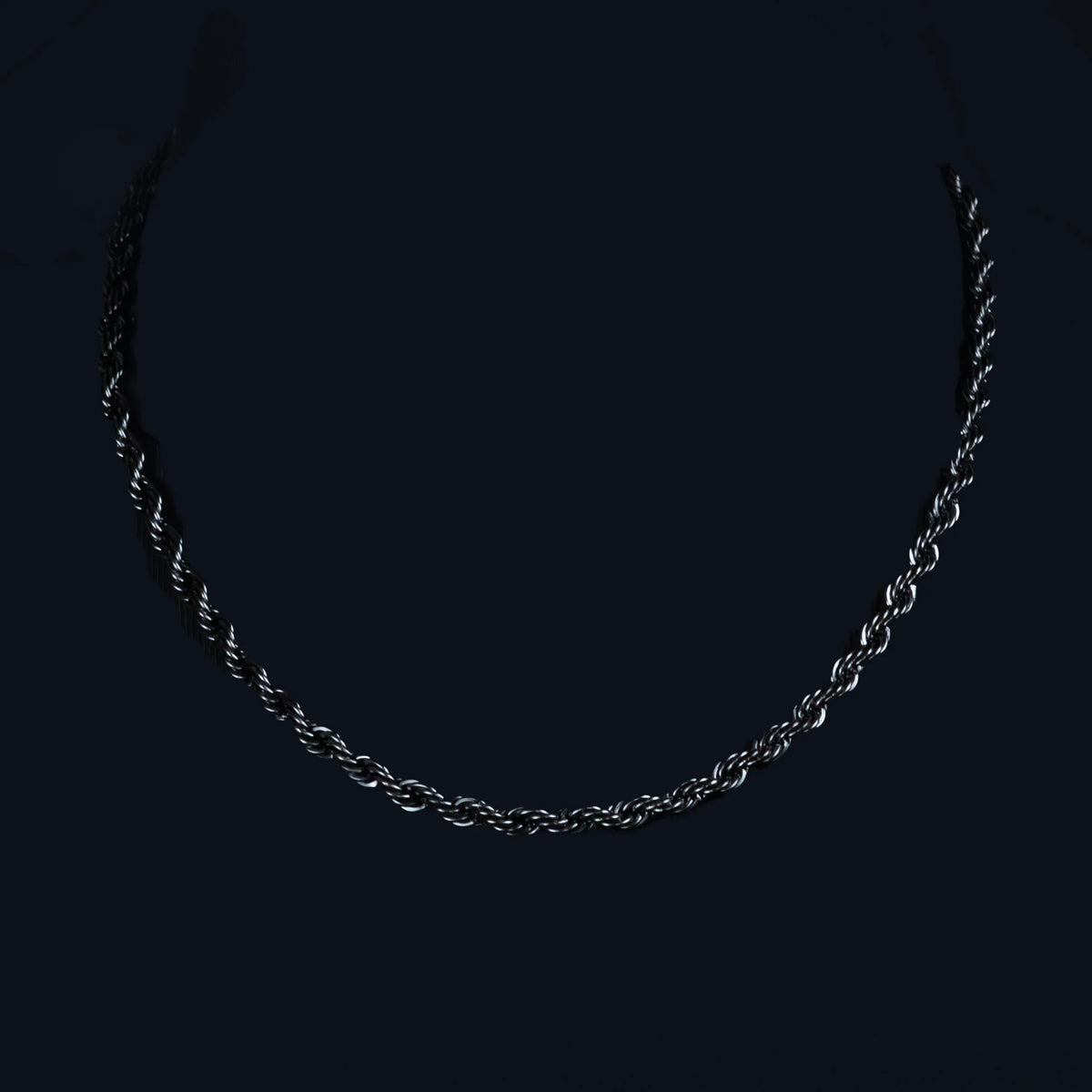 Silver chain necklace against a dark background.