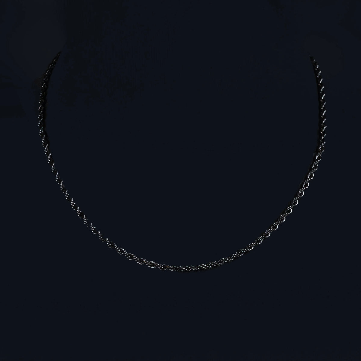 Silver chain necklace against a dark background.