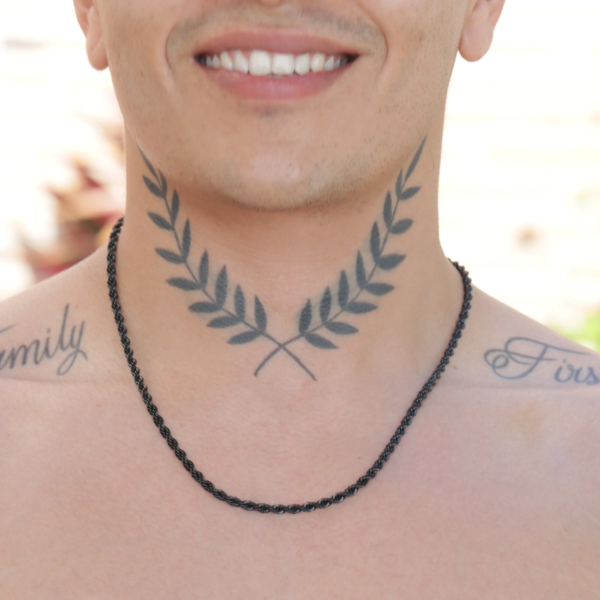 Tattoo of crossed laurel branches on a person’s neck.