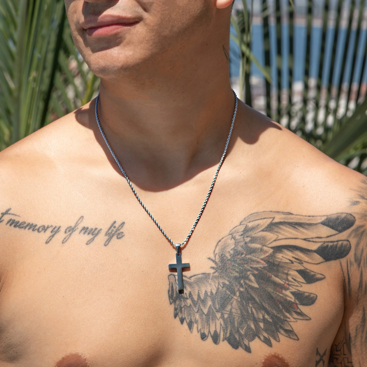 Shirtless torso with tattoos and a cross necklace.