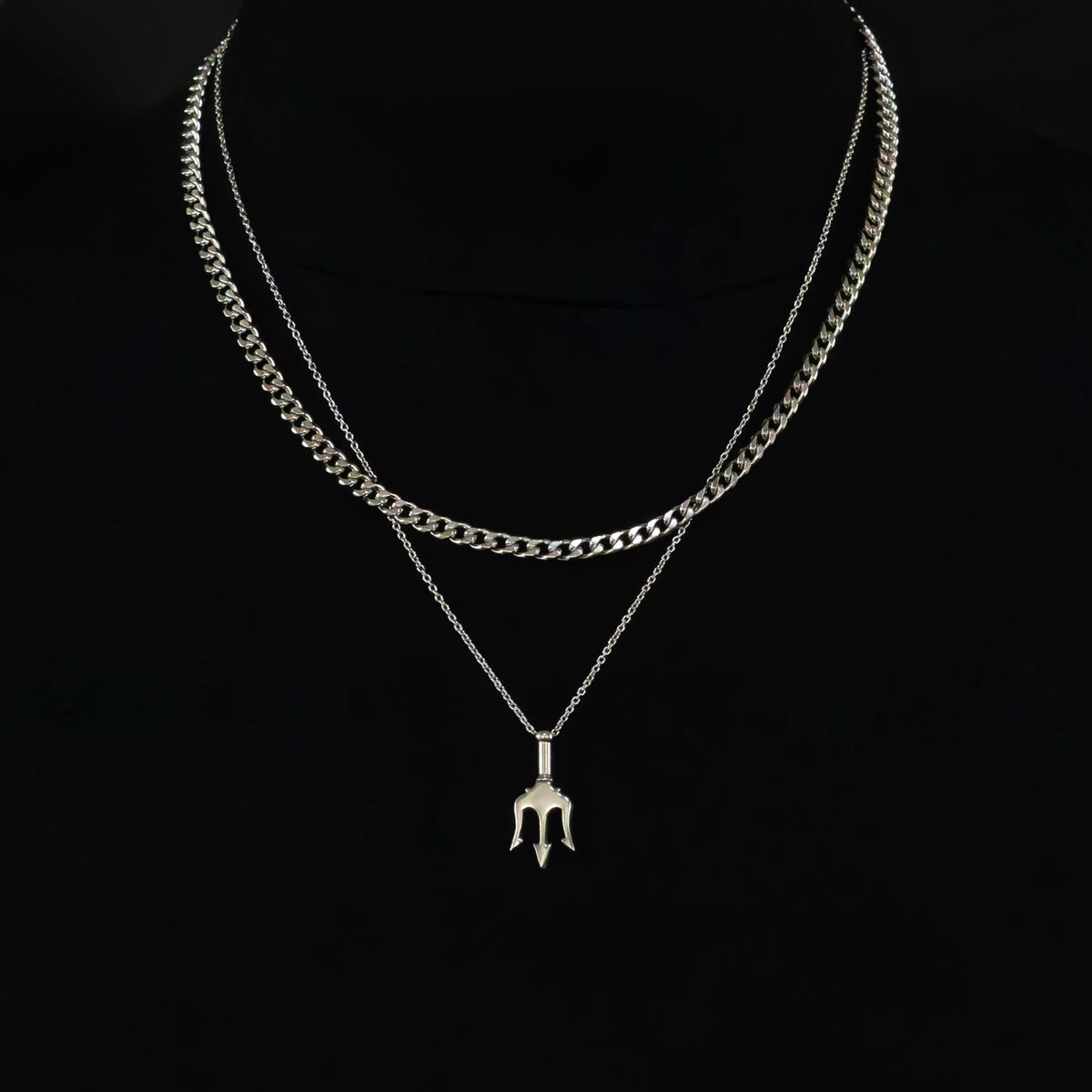 Layered silver necklace with a trident-shaped pendant.