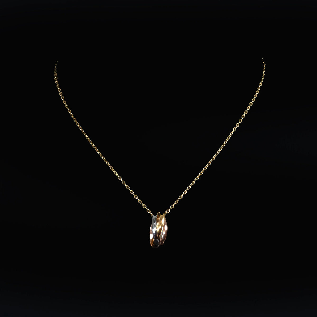 Delicate gold necklace with a tri-color twisted ring pendant.