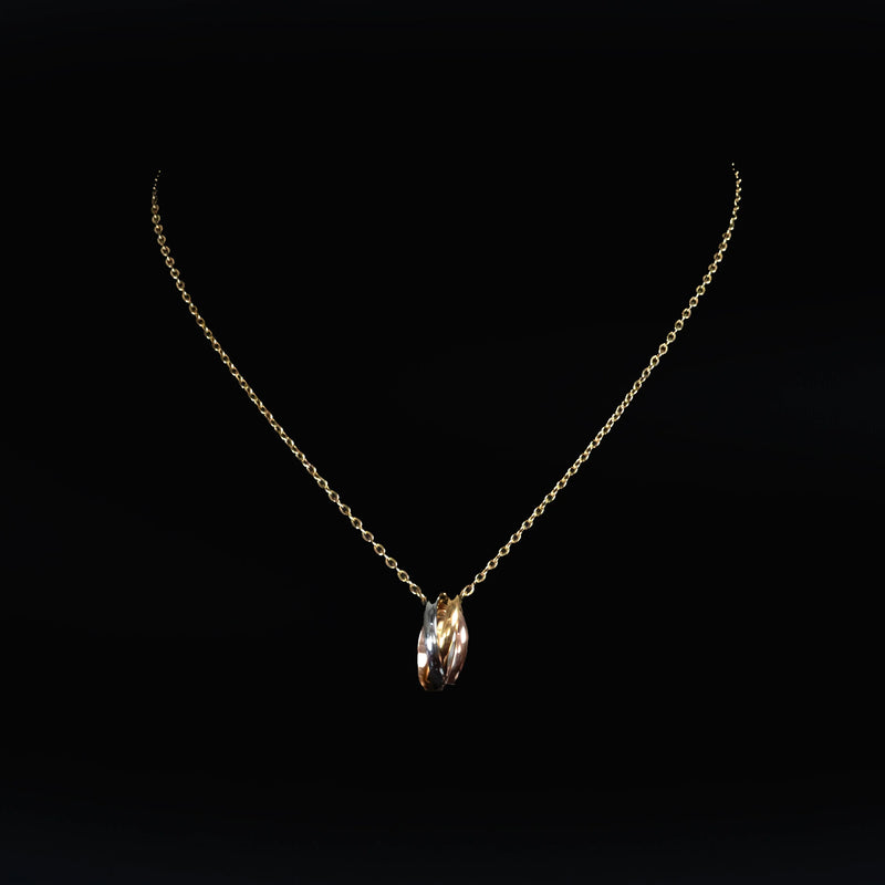 Delicate gold necklace with a tri-color twisted ring pendant.