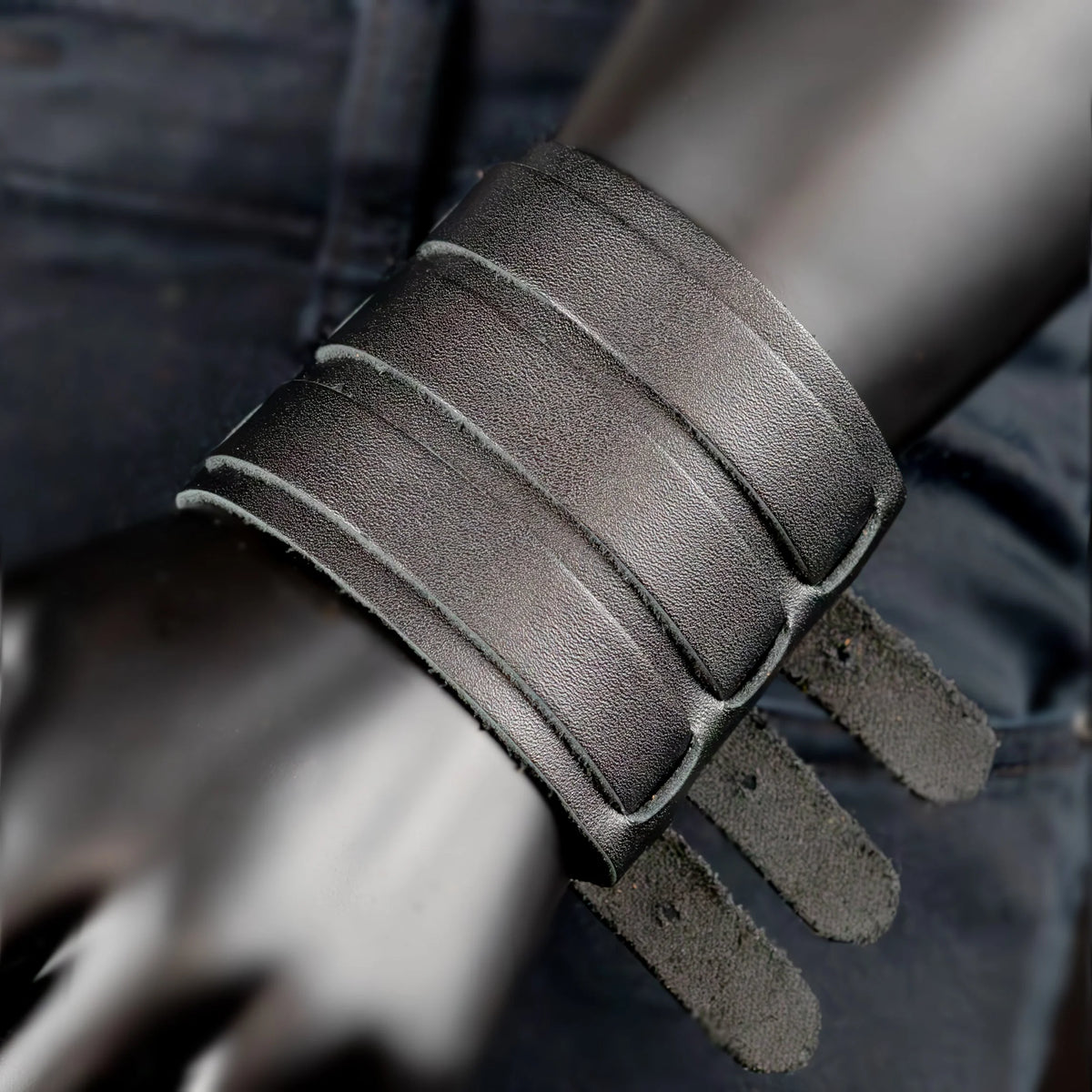 Gray leather cuff bracelet with multiple straps and buckles.