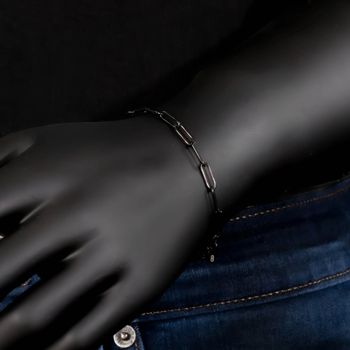 Silver chain bracelet on a black mannequin hand.