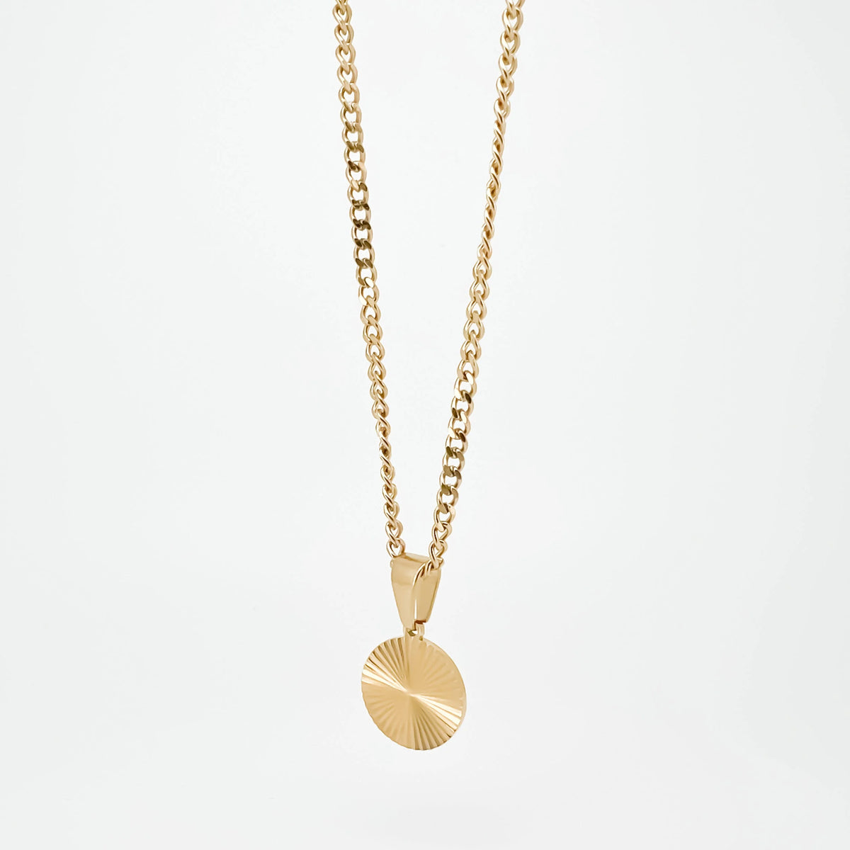 Gold necklace with a circular pendant featuring a sunburst pattern.