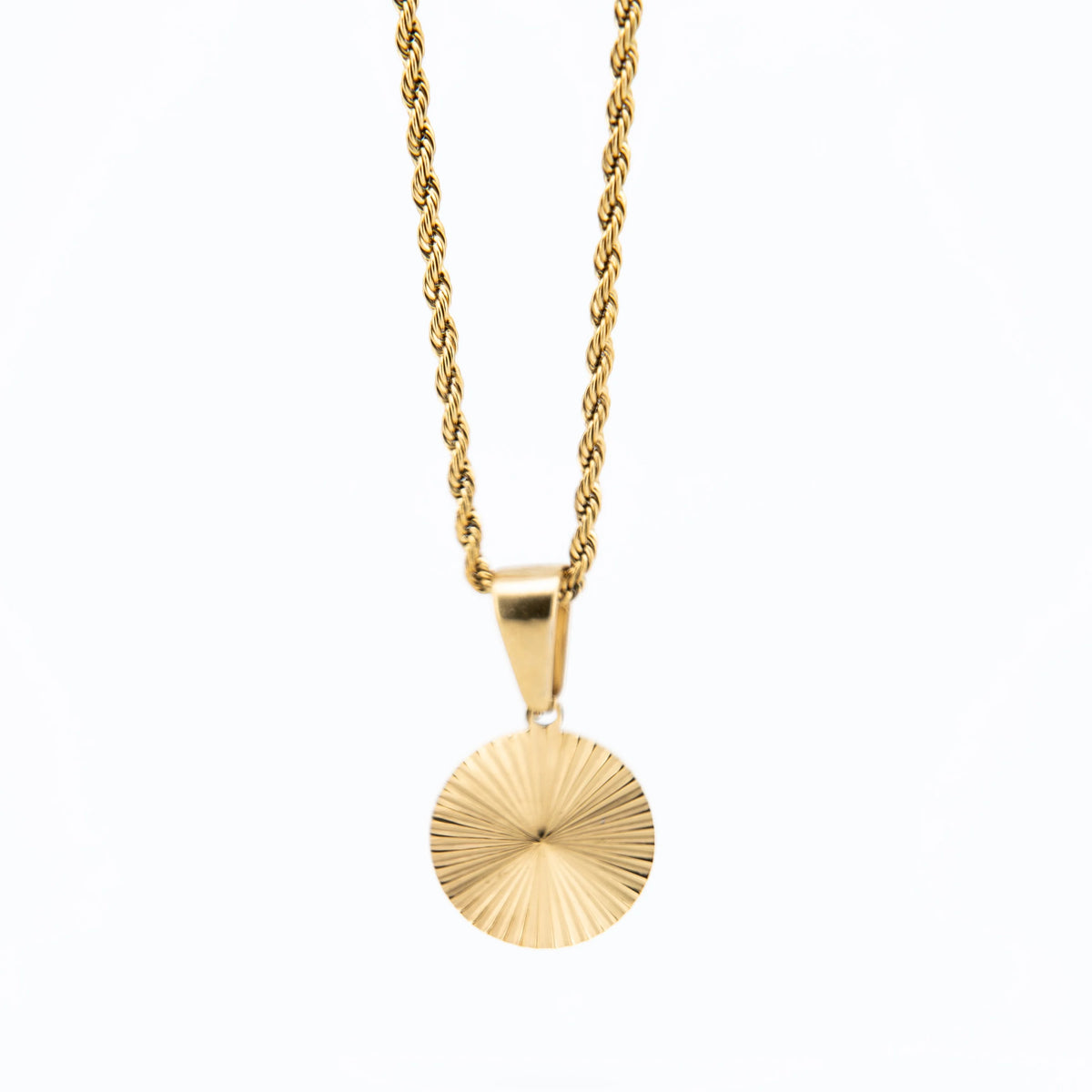 Gold pendant necklace with a circular, sunburst-patterned charm.