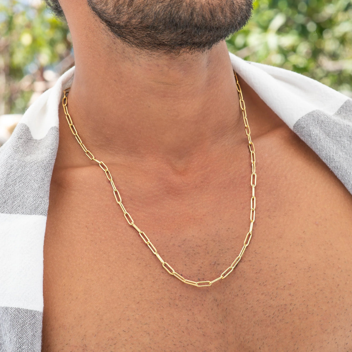 Gold paperclip-style chain necklace worn around a neck.