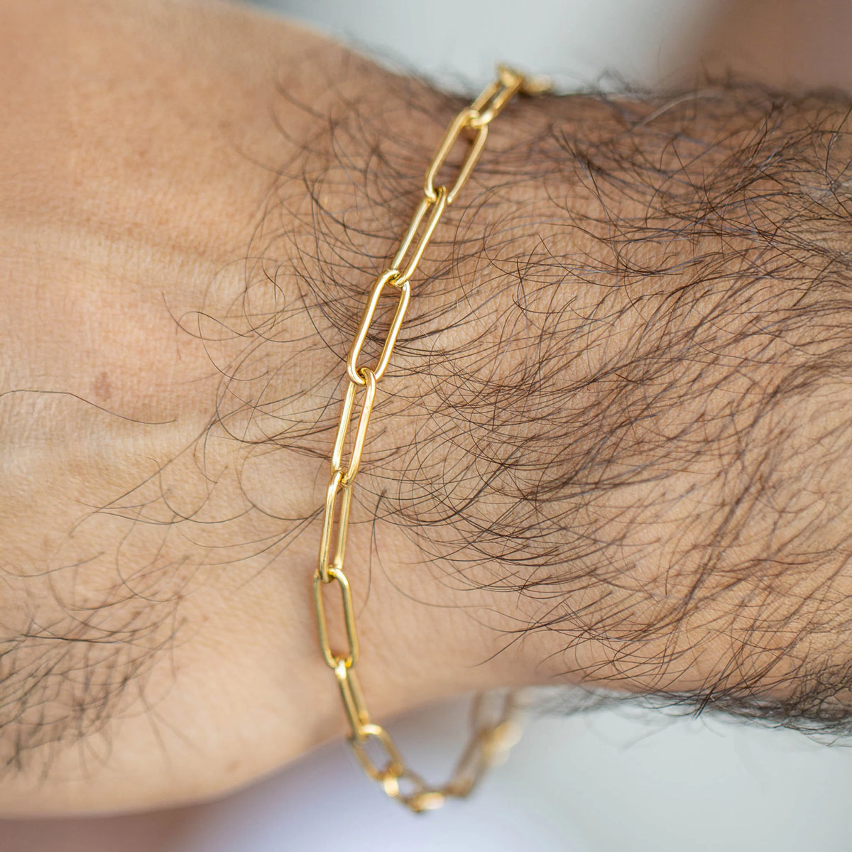 Gold chain-link bracelet worn on a wrist.