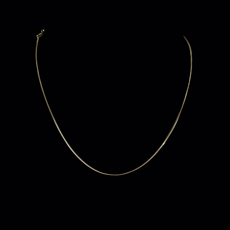 Simple silver chain necklace against dark background.