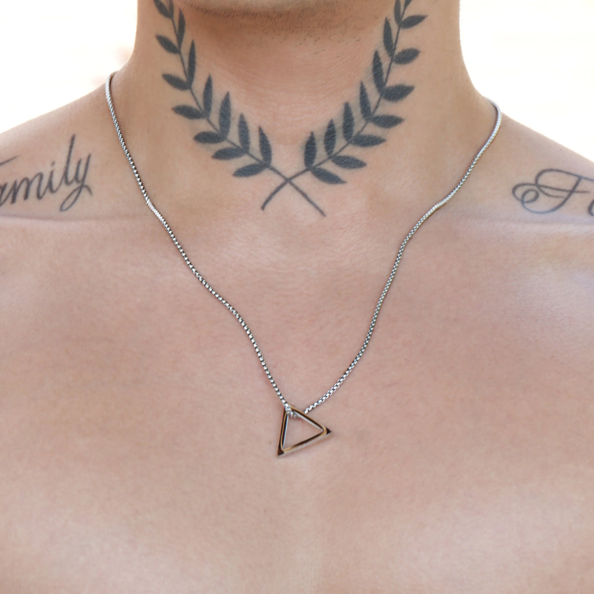 Simple silver chain necklace with a triangular pendant.