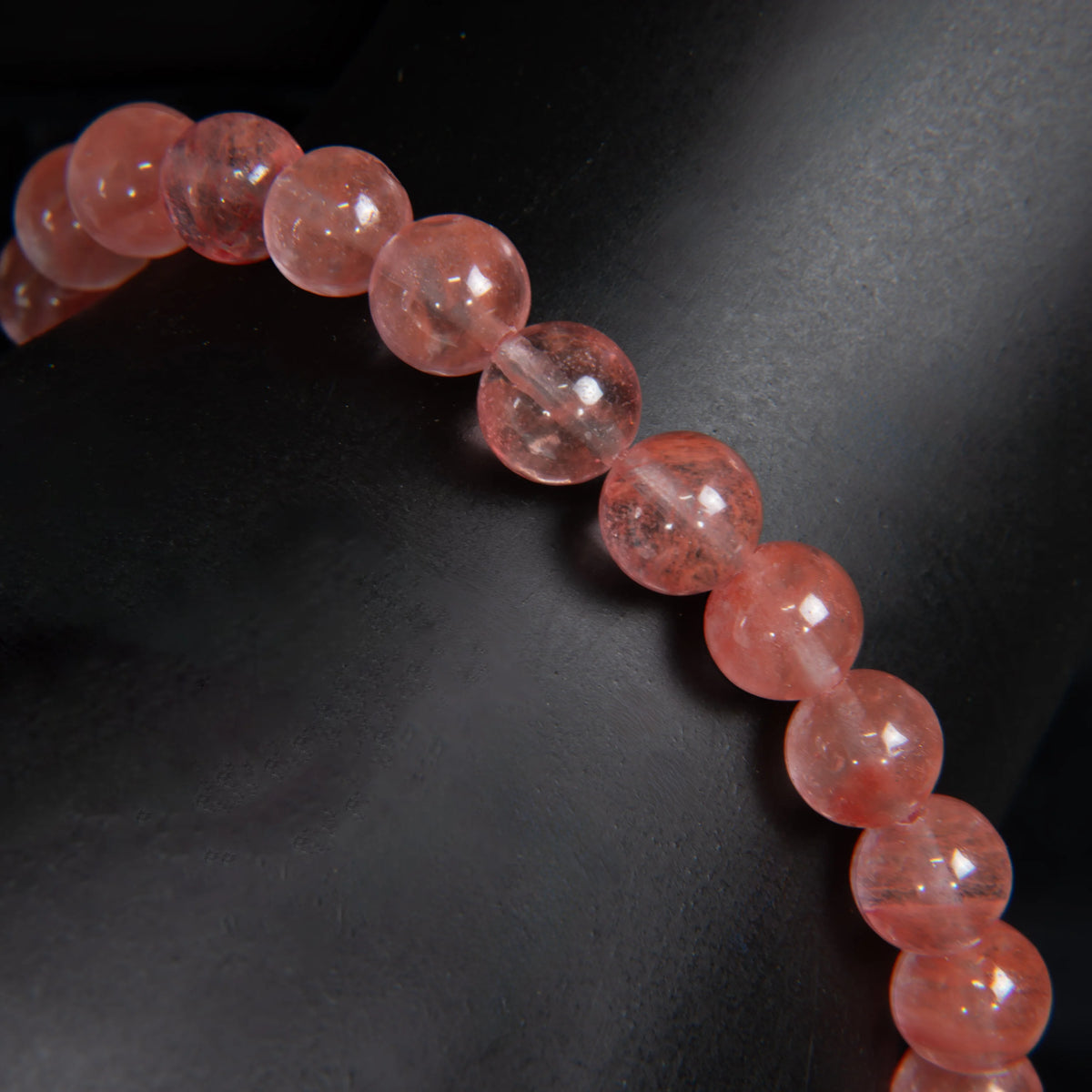 String of translucent pink beads or gemstones arranged in a curved line.