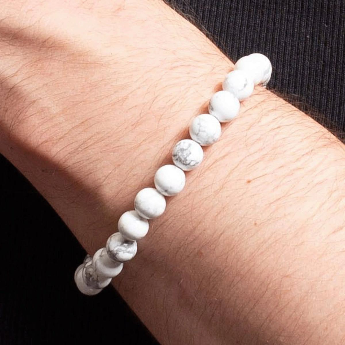 White marble or howlite beaded bracelet worn on a wrist.