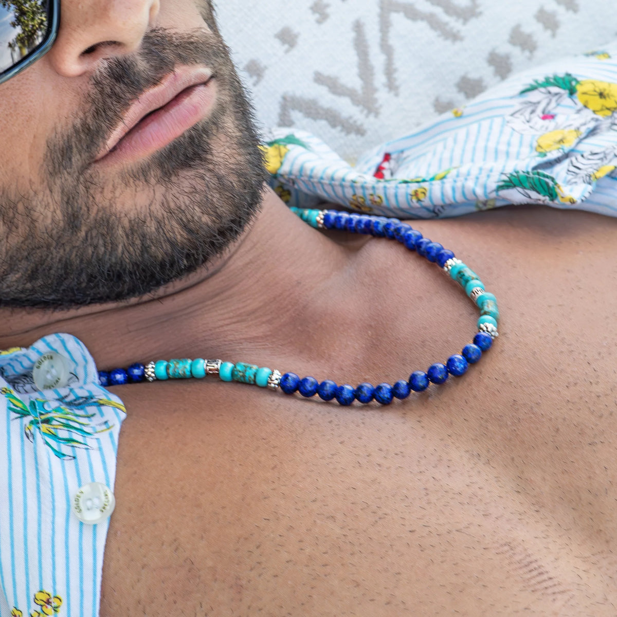 Colorful beaded necklace with blue and turquoise beads worn around a person’s neck.