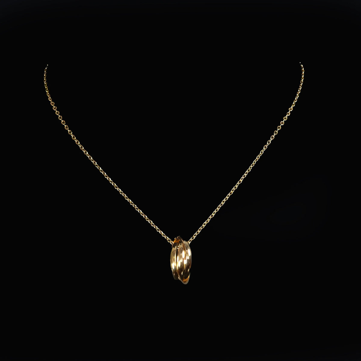 Gold necklace with interlocking ring pendant on delicate chain.