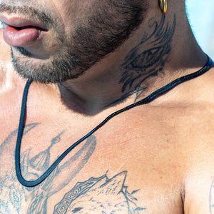 Black cord necklace against tattooed skin.