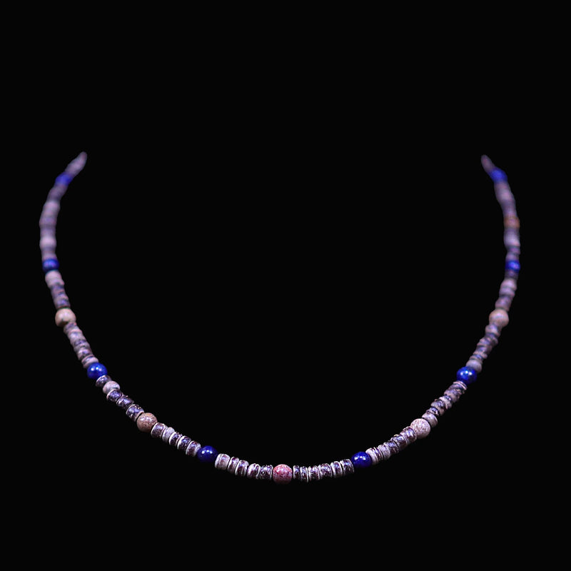 Beaded necklace with purple, blue, and pink stones on a black background.