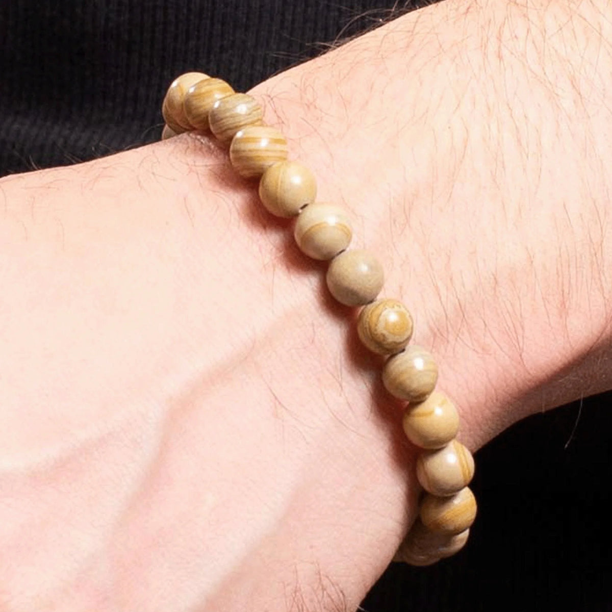 Beaded bracelet made of light-colored wooden or stone beads worn on a wrist.