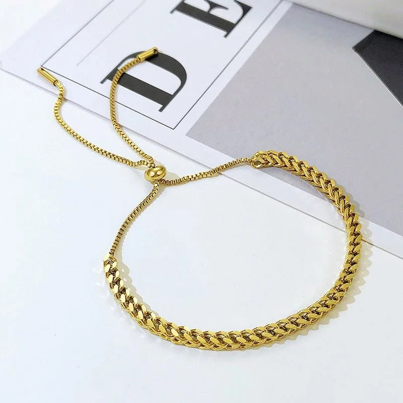 Gold-colored adjustable chain bracelet with a woven pattern.