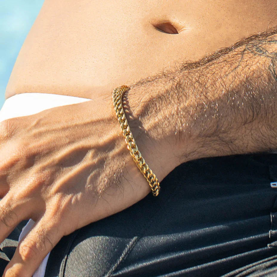 Gold chain bracelet worn on a wrist.