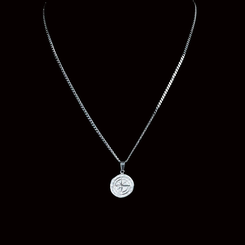 Silver necklace with a round compass pendant.